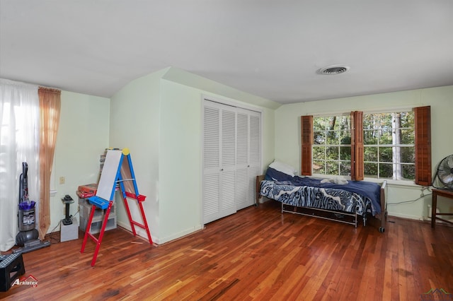 bedroom with hardwood / wood-style floors, a closet, and lofted ceiling