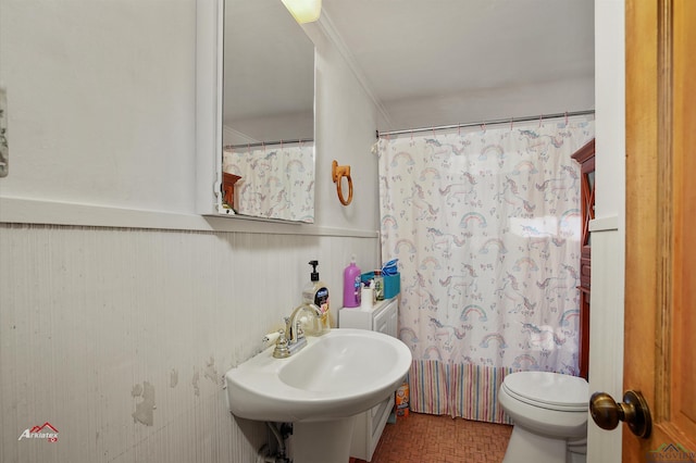 bathroom featuring a shower with curtain, toilet, ornamental molding, and sink