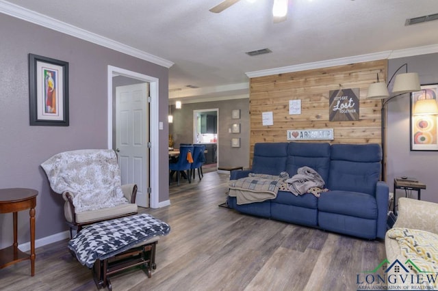 living room featuring crown molding, ceiling fan, wooden walls, and hardwood / wood-style floors