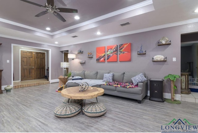 living room with crown molding, ceiling fan, a tray ceiling, and hardwood / wood-style floors