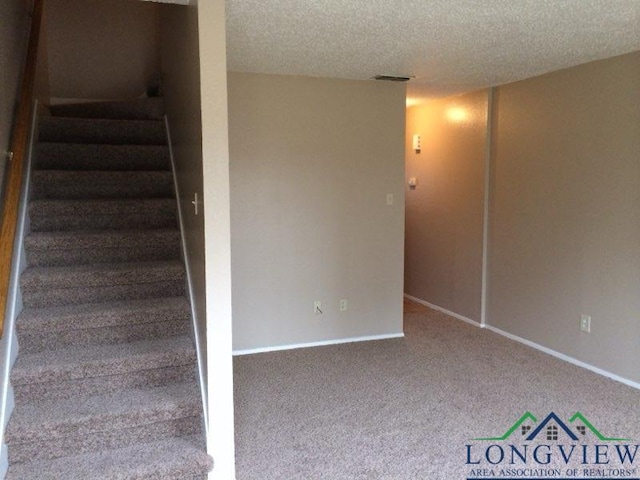 stairs featuring carpet flooring and a textured ceiling