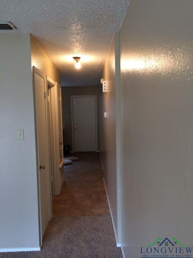 hallway featuring carpet and a textured ceiling