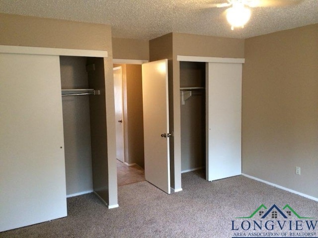 unfurnished bedroom with carpet, a textured ceiling, and multiple closets