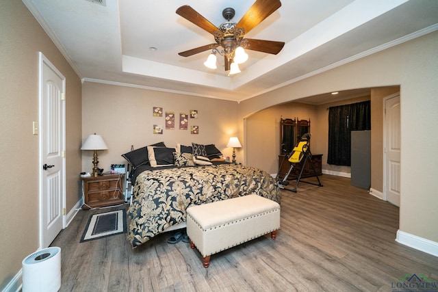 1901 Azalea St, Gilmer, TX 75644 - bedroom with baseboards, wood finished floors, arched walkways, and a tray ceiling