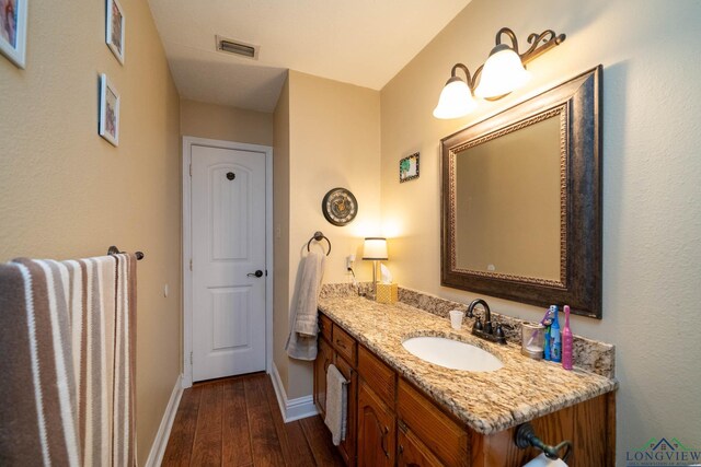 1901 Azalea St, Gilmer, TX 75644 - bathroom featuring baseboards, vanity, wood finished floors, and visible vents