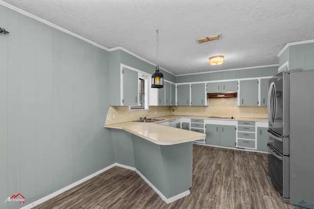 kitchen featuring stainless steel refrigerator, hanging light fixtures, dark hardwood / wood-style floors, kitchen peninsula, and a textured ceiling