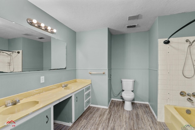 full bathroom featuring vanity, a textured ceiling, hardwood / wood-style floors, toilet, and tiled shower / bath