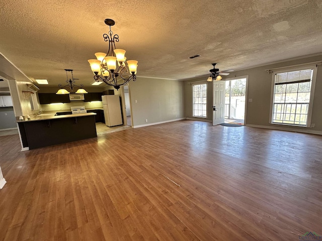 587 Floyd Evans Rd, Marshall, TX 75672 - unfurnished living room with visible vents, ceiling fan with notable chandelier, a textured ceiling, wood finished floors, and baseboards