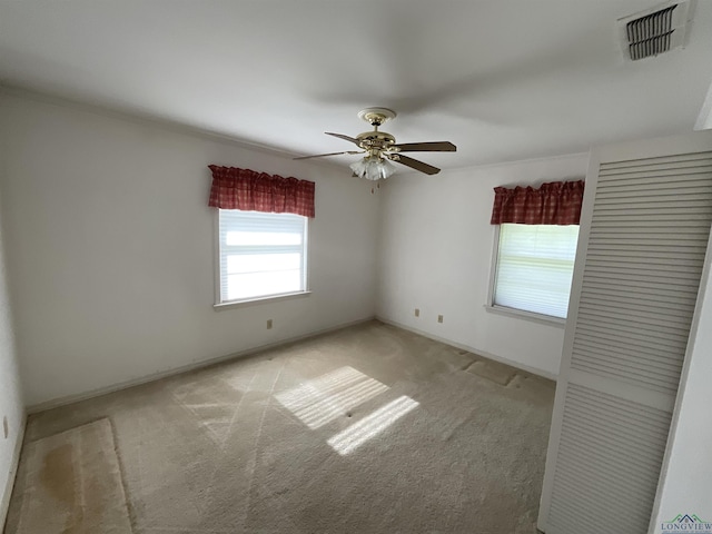 spare room featuring light colored carpet and ceiling fan