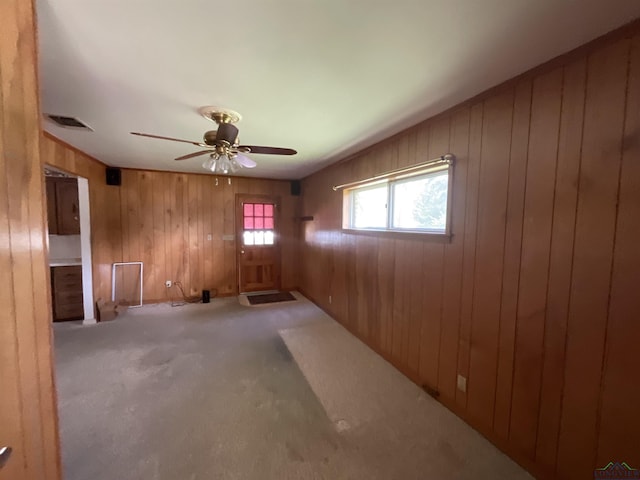 carpeted spare room featuring ceiling fan and wood walls