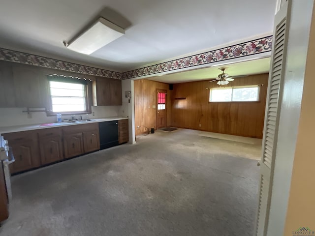 kitchen with black dishwasher, light colored carpet, ceiling fan, and wooden walls