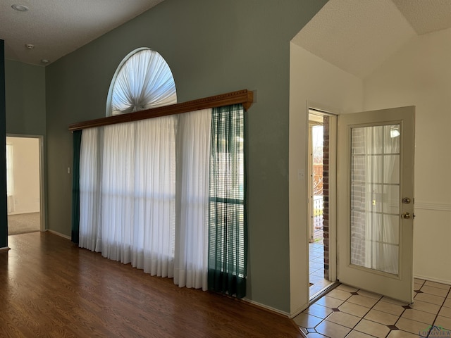 entrance foyer with vaulted ceiling, a healthy amount of sunlight, and a textured ceiling