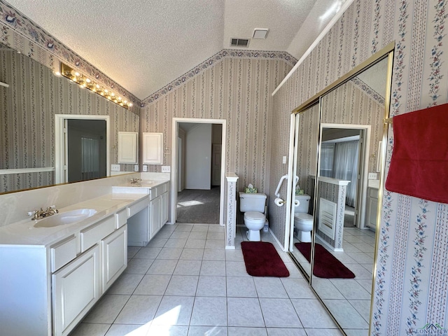 bathroom featuring lofted ceiling, vanity, a textured ceiling, tile patterned floors, and toilet