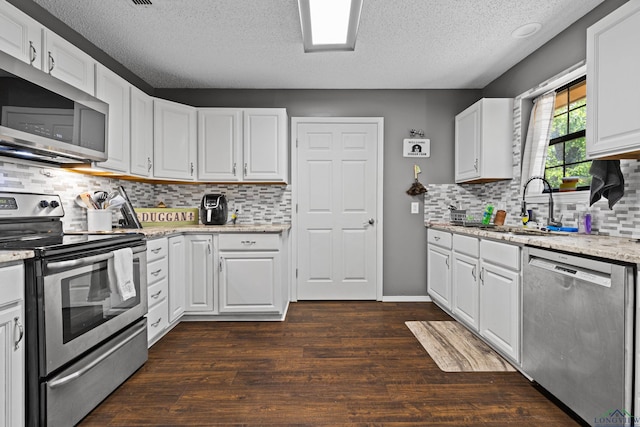 kitchen with a textured ceiling, white cabinetry, a sink, dark wood finished floors, and stainless steel appliances