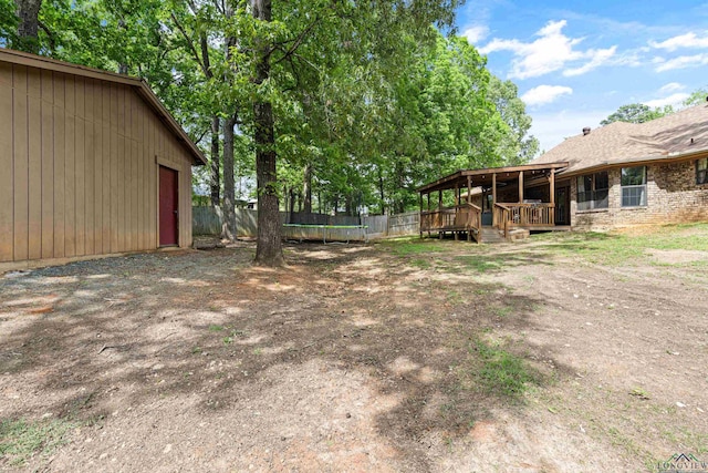 view of yard featuring fence, a trampoline, a deck, and a garage