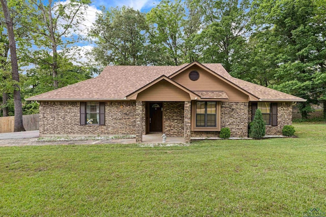 ranch-style house with brick siding, fence, a shingled roof, and a front yard