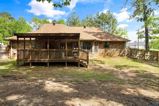 rear view of property featuring a ceiling fan, roof with shingles, a deck, brick siding, and a fenced backyard