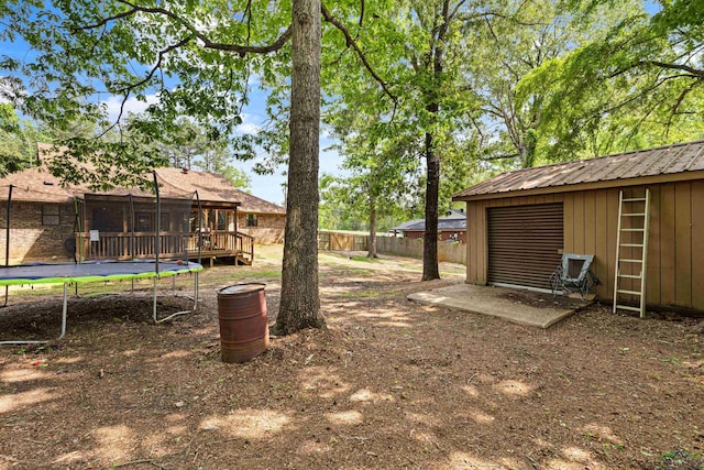 view of yard featuring fence, an outdoor structure, and a trampoline