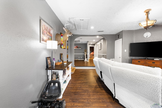 living room with a textured wall, arched walkways, recessed lighting, baseboards, and wood finished floors
