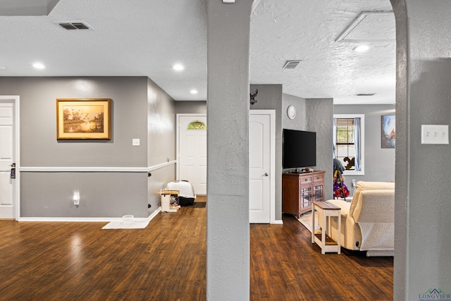 living area with baseboards, a textured ceiling, visible vents, and wood finished floors