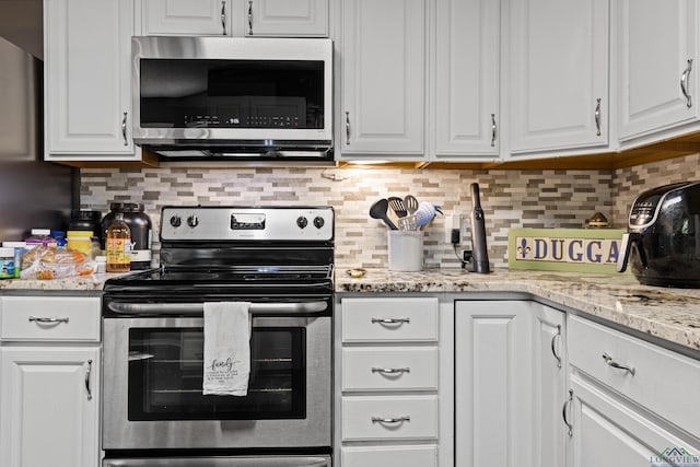 kitchen with white cabinets, stainless steel appliances, light stone counters, and decorative backsplash