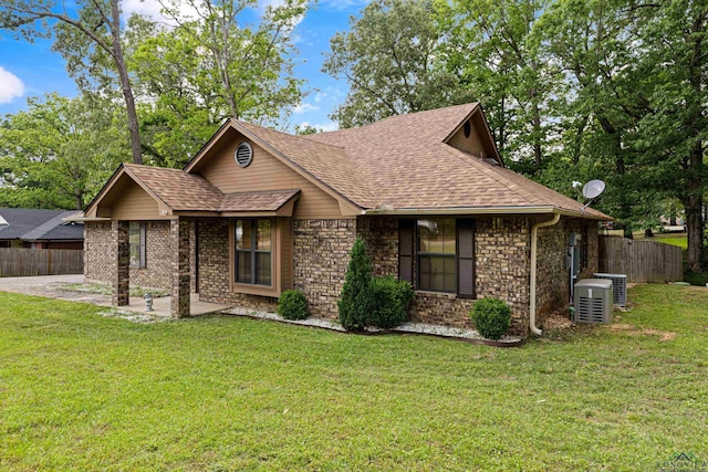 view of front of house with fence, a patio, a shingled roof, and a front yard