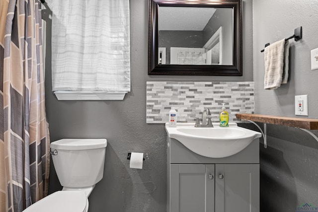 full bath featuring vanity, a textured wall, backsplash, and toilet