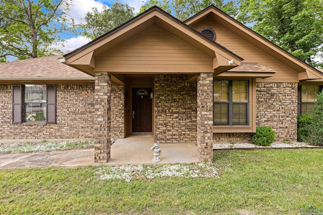 ranch-style house with brick siding, a shingled roof, and a front lawn