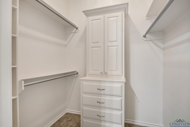 walk in closet featuring dark carpet