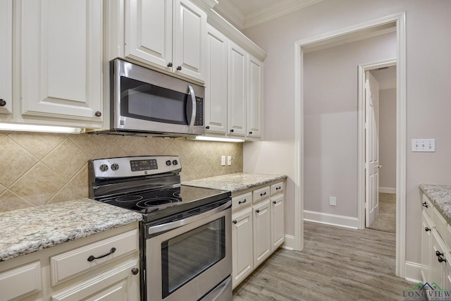 kitchen with appliances with stainless steel finishes, white cabinetry, decorative backsplash, light stone counters, and crown molding