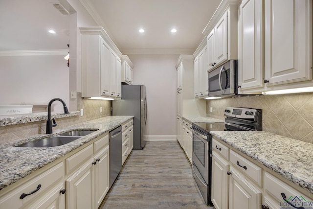 kitchen featuring sink, crown molding, stainless steel appliances, and white cabinetry