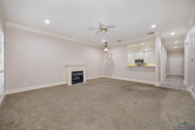 unfurnished living room featuring light carpet, ceiling fan, and ornamental molding