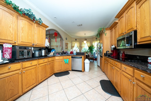 kitchen featuring ornamental molding, stainless steel appliances, sink, pendant lighting, and dark stone countertops