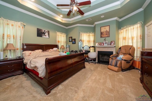 carpeted bedroom with a raised ceiling, ceiling fan, and ornamental molding