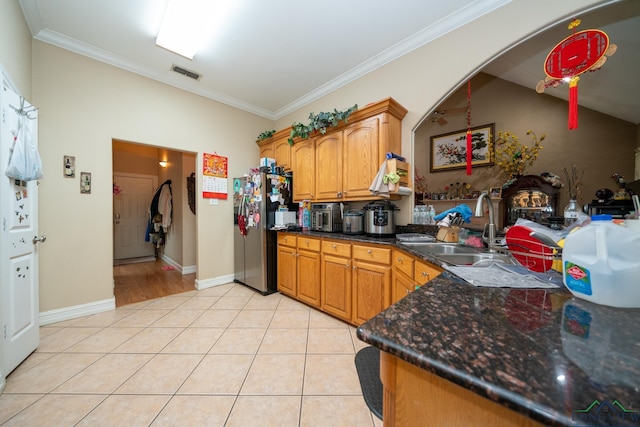 kitchen featuring stainless steel fridge, light tile patterned floors, ornamental molding, and sink