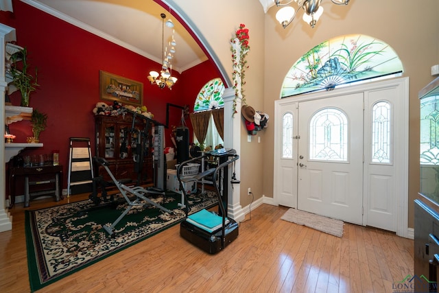 entryway with ornamental molding, wood-type flooring, and a notable chandelier