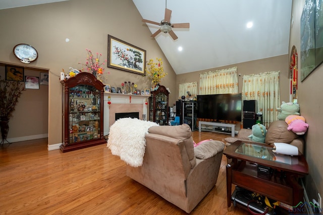 living room with ceiling fan, light wood-type flooring, and high vaulted ceiling