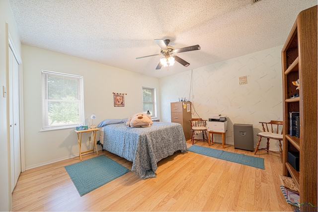 bedroom featuring hardwood / wood-style flooring, ceiling fan, and a textured ceiling