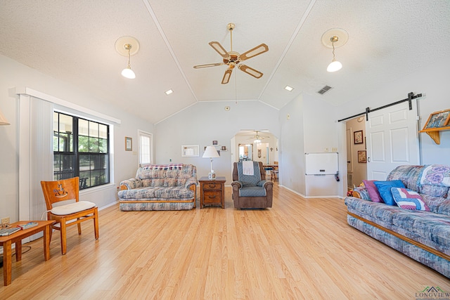 living room with hardwood / wood-style flooring, a barn door, a textured ceiling, and vaulted ceiling