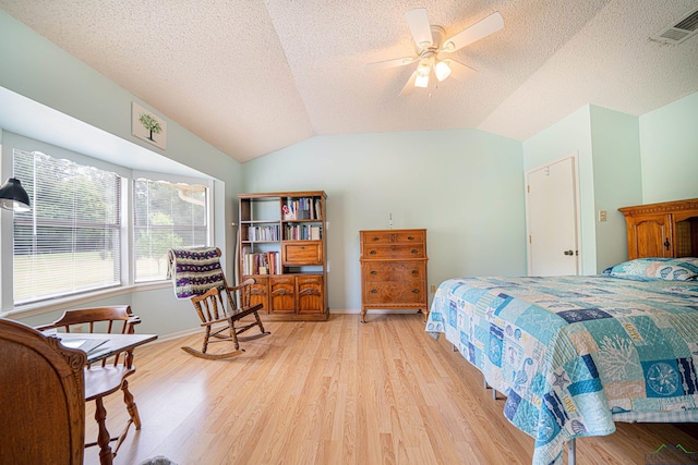 bedroom featuring ceiling fan, lofted ceiling, a textured ceiling, and light hardwood / wood-style flooring