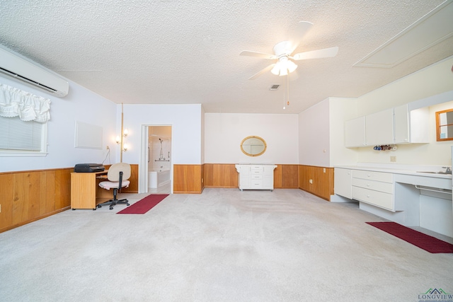 carpeted office featuring a wall mounted air conditioner, a textured ceiling, ceiling fan, and wood walls