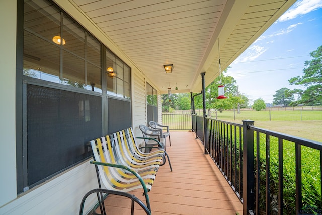 wooden terrace featuring covered porch and a lawn