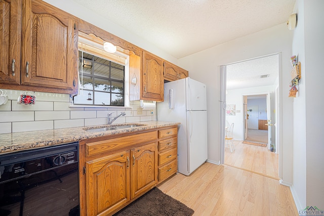 kitchen featuring light wood-type flooring, tasteful backsplash, sink, white refrigerator, and black dishwasher