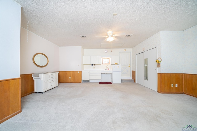 living room with a textured ceiling, light carpet, and wooden walls