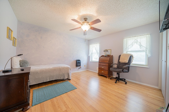 bedroom featuring hardwood / wood-style floors, ceiling fan, a textured ceiling, and heating unit