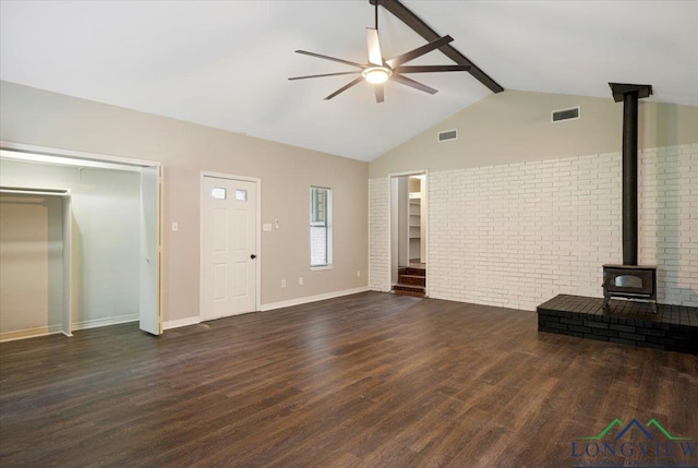 1012 Premier Rd, Longview, TX 75604 - unfurnished living room with a ceiling fan, a wood stove, wood finished floors, brick wall, and baseboards