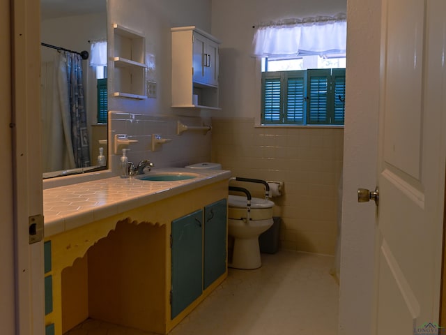bathroom with toilet, a wainscoted wall, a shower with curtain, vanity, and tile walls