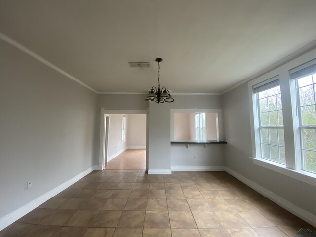 unfurnished dining area featuring crown molding, tile patterned floors, and an inviting chandelier