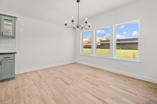 unfurnished dining area featuring a notable chandelier and light hardwood / wood-style flooring