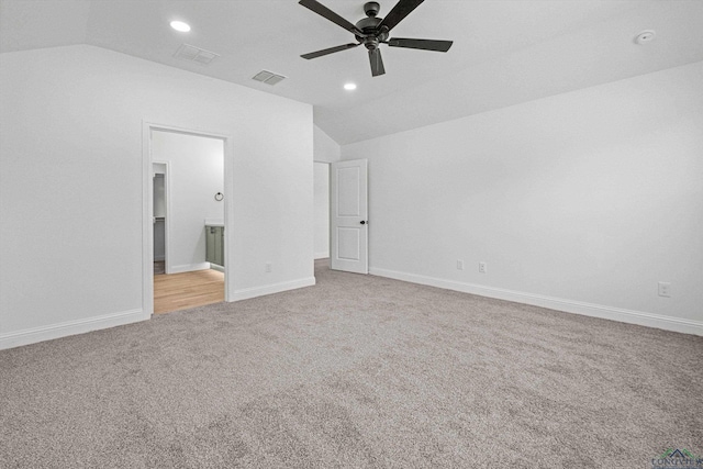 unfurnished bedroom featuring ceiling fan, light colored carpet, ensuite bathroom, and lofted ceiling